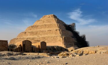 Step Pyramid of Djoser in Saqqara under restoration with clear blue sky.