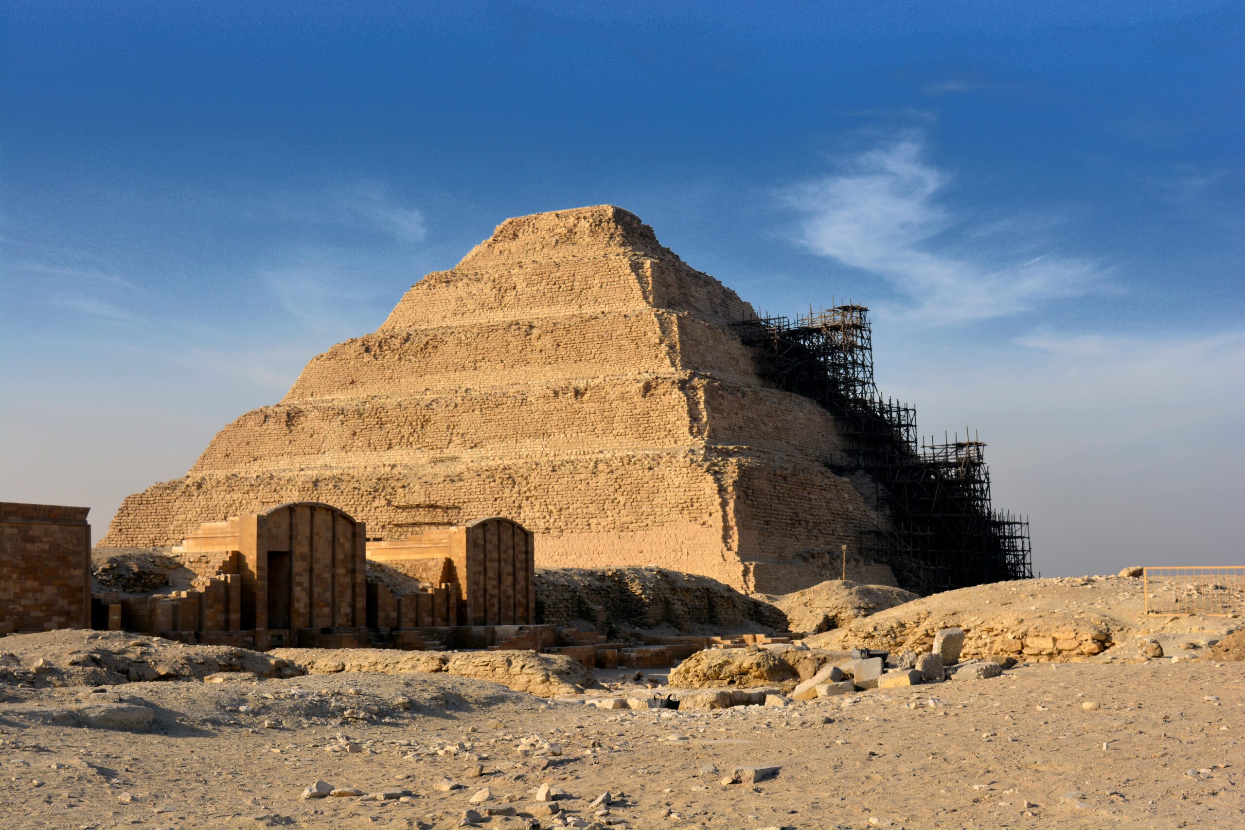 Step Pyramid of Djoser in Saqqara under restoration with clear blue sky.